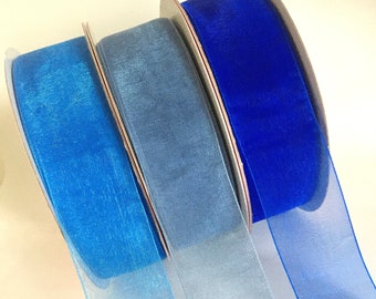 May include: Three rolls of sheer ribbon in shades of blue. The ribbon is a light blue, a medium blue, and a dark blue.