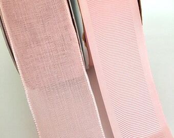 Könnte beinhalten: Zwei Rollen rosa Band, eine mit einer strukturierten Webart und die andere mit einer gerippten Textur.