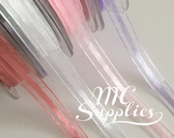 May include: Four spools of sheer ribbon with a satin stripe. The ribbons are in shades of lavender, pink, white, and coral.