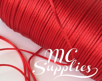 May include: A spool of red satin cord, with a length of the cord lying on a white surface. The spool is labeled "MC Supplies".