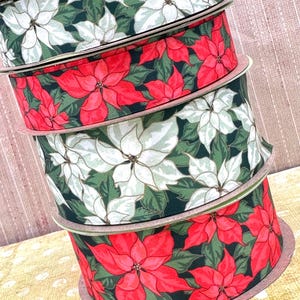 May include: Four spools of Christmas ribbon with a poinsettia print. The ribbon is red, white, and green.