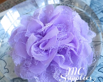 May include: A light purple flower made of lace fabric. The flower is sitting on a clear glass surface. The text "MC Supplies" is visible in the bottom right corner of the image.