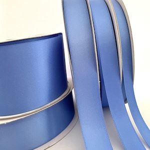 May include: Four spools of light blue satin ribbon. The ribbon is wound around cardboard spools.