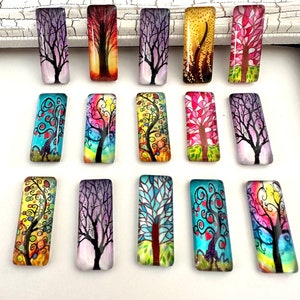 May include: Assortment of 15 rectangular glass cabochons featuring colorful, whimsical tree designs. Each cabochon has a different tree design with various colors and patterns.