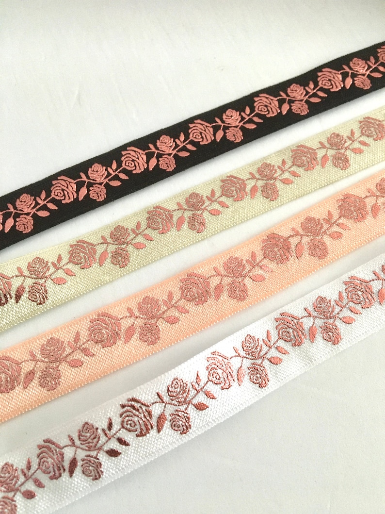 May include: Four different colors of ribbon with a rose pattern. The ribbon is a light cream, peach, white, and black. The roses are a metallic copper color.