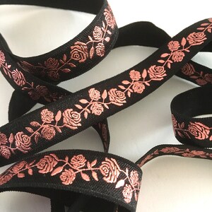 May include: Black elastic ribbon with a rose pattern in a metallic rose gold color.