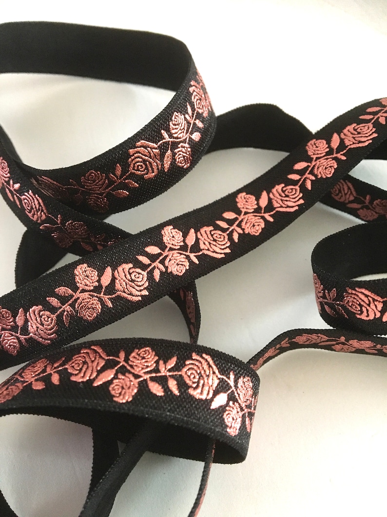 May include: Black elastic ribbon with a rose pattern in a metallic rose gold color.