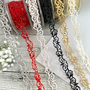 May include: Five spools of decorative trim with intricate floral designs. The trim is available in red, white, black, gold, and ivory.