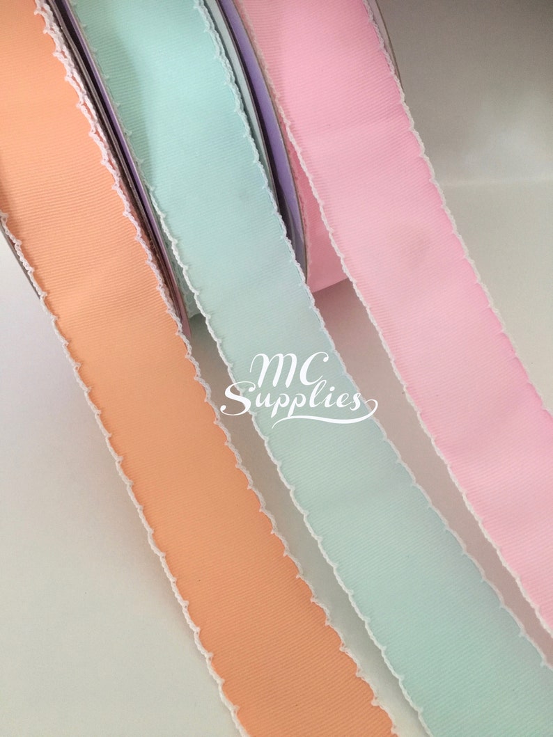May include: Close-up of three spools of ribbon in pastel colours: peach, mint green, and pink. Each ribbon has a textured surface and a white, frayed edge. The text "MC Supplies" is visible in the image.