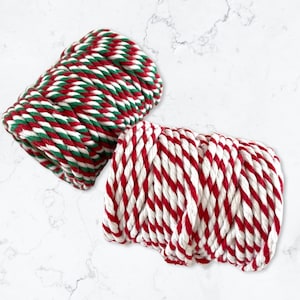 May include: Two spools of red and white striped cotton rope. One spool has green stripes and the other has white stripes.