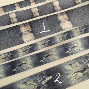 May include: Five strips of blue and white denim-patterned ribbon. The ribbon has a distressed look with white patches that resemble rips in denim. The ribbon is numbered 1 and 2.
