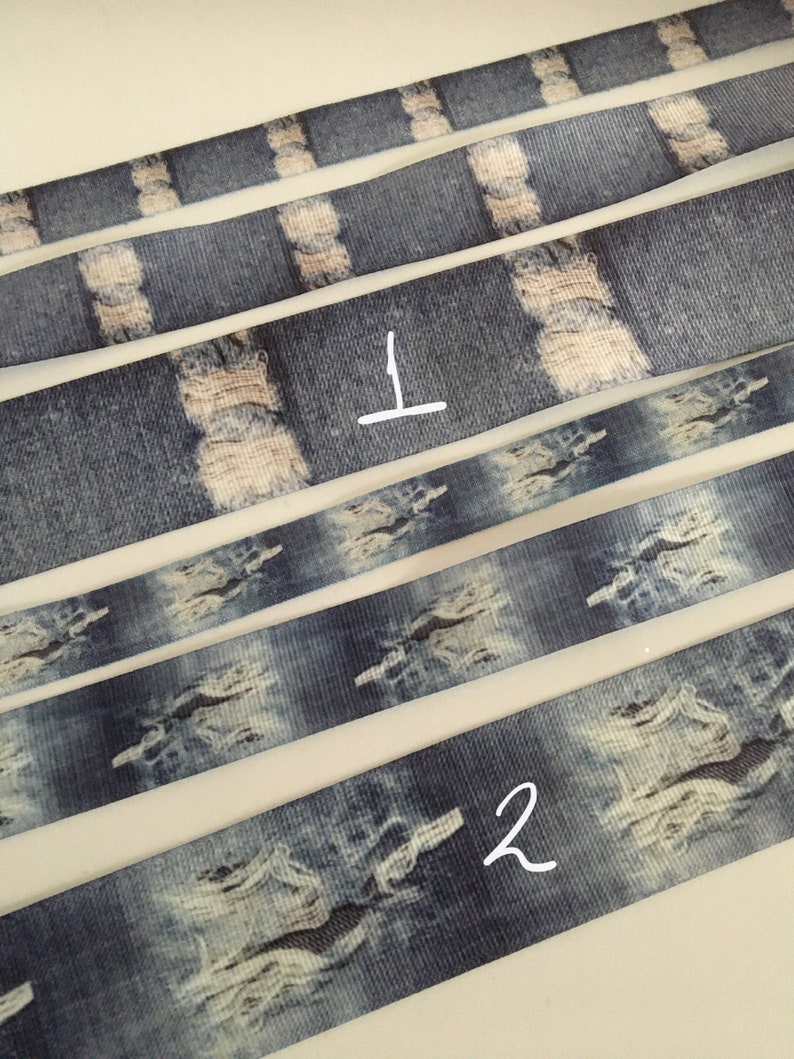 May include: Five strips of blue and white denim-patterned ribbon. The ribbon has a distressed look with white patches that resemble rips in denim. The ribbon is numbered 1 and 2.