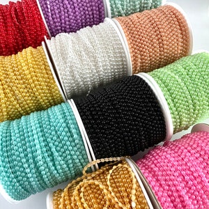 May include: Spools of pearl bead trim in various colors, including red, purple, white, peach, green, black, light blue, gold, and pink.
