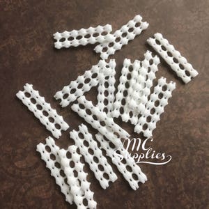 May include: White plastic mesh strips, ideal for crafting projects. The strips are approximately 1.5 inches wide and have a honeycomb pattern.