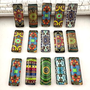 May include: Assortment of 15 colorful rectangular glass tiles with intricate geometric patterns. The tiles feature a variety of colors, including red, blue, green, yellow, and black.
