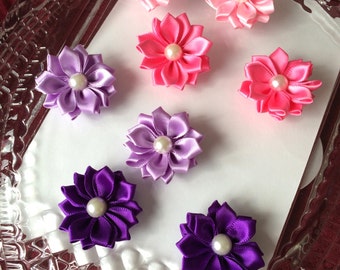 May include: Eight handmade fabric flower hair clips in pink and purple. The flowers have a layered design and a pearl center.