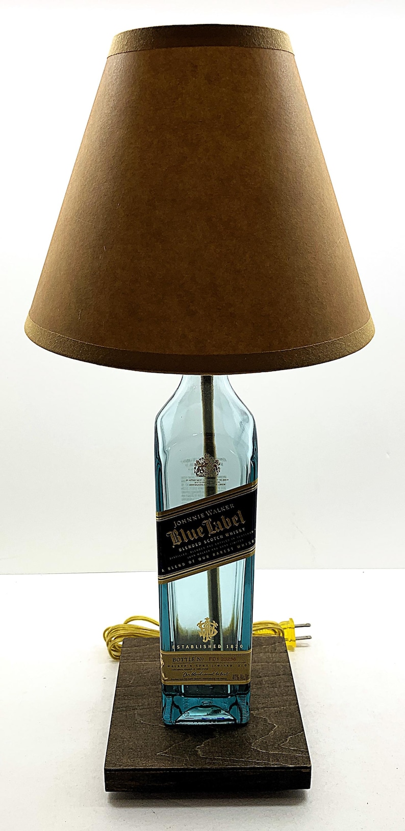 K&ouml;nnte beinhalten: Eine einzigartige Tischlampe aus einer recycelten Johnnie Walker Blue Label Whiskyflasche. Die Lampe hat einen braunen Lampenschirm und steht auf einem dunklen Holzsockel. Das Etikett der Flasche ist sichtbar.