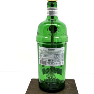 May include: A green glass bottle lamp with a gold light fixture and a brown wooden base. The bottle is labeled "Tanqueray London Dry Gin" and "Charles Tanqueray & Co."