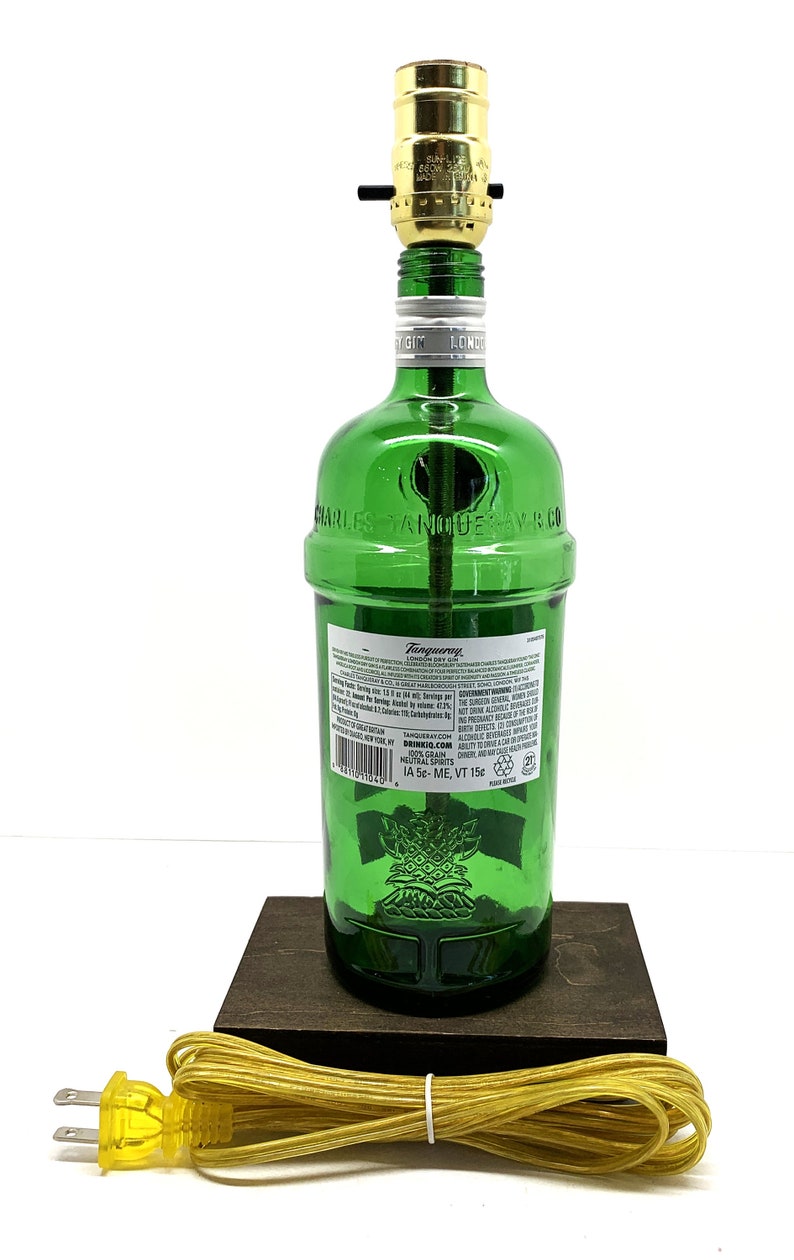 May include: A green glass bottle lamp with a gold light fixture and a brown wooden base. The bottle is labeled "Tanqueray London Dry Gin" and "Charles Tanqueray & Co."