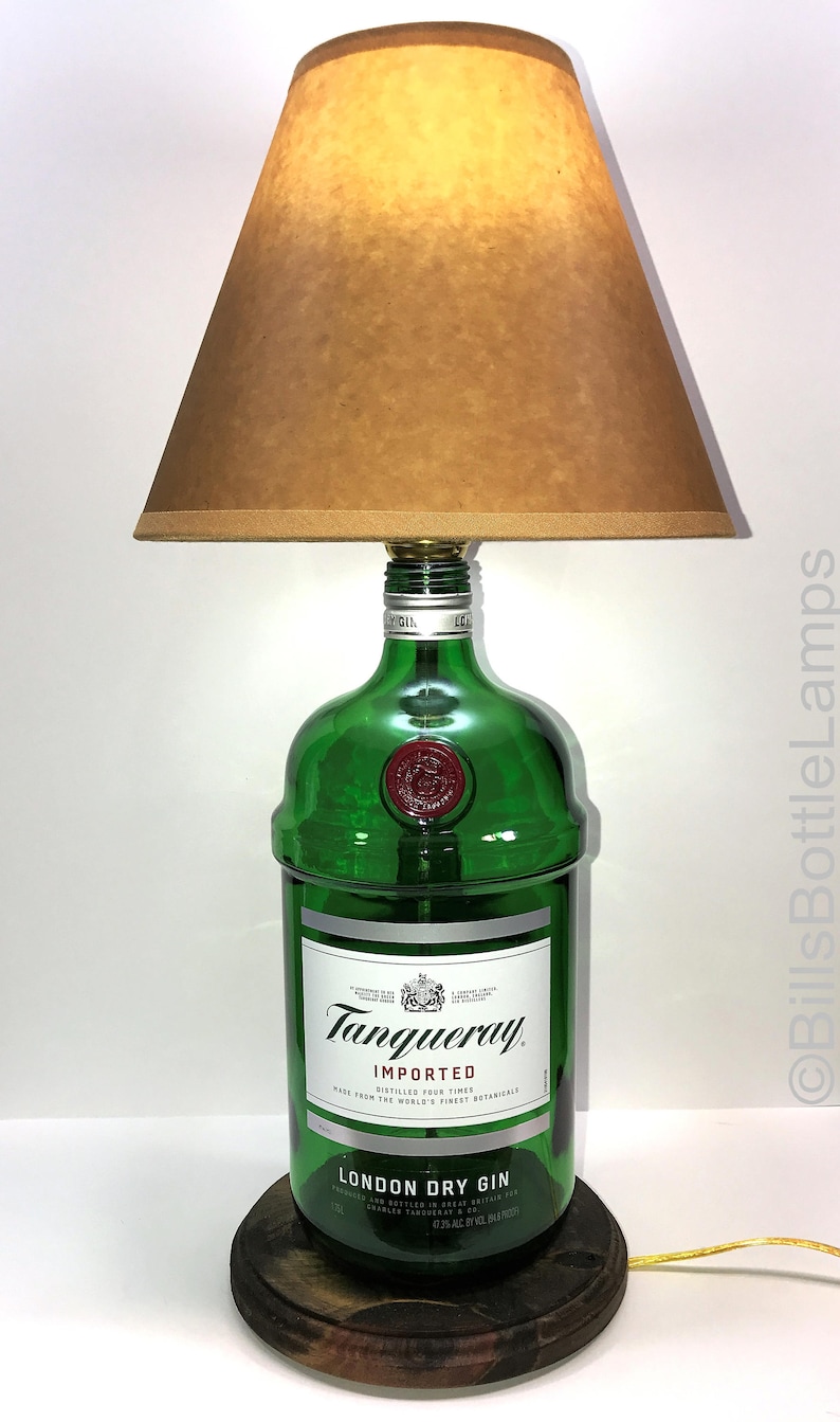 Puede incluir: Una l&aacute;mpara de botella de vidrio verde con una pantalla marr&oacute;n. La botella est&aacute; etiquetada con "Tanqueray Imported London Dry Gin".
