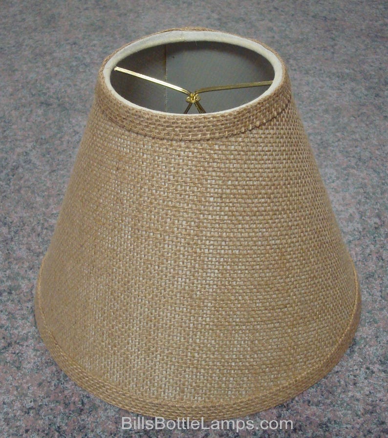 May include: A brown burlap lampshade with a wire frame. The lampshade is cone-shaped and has a simple design.
