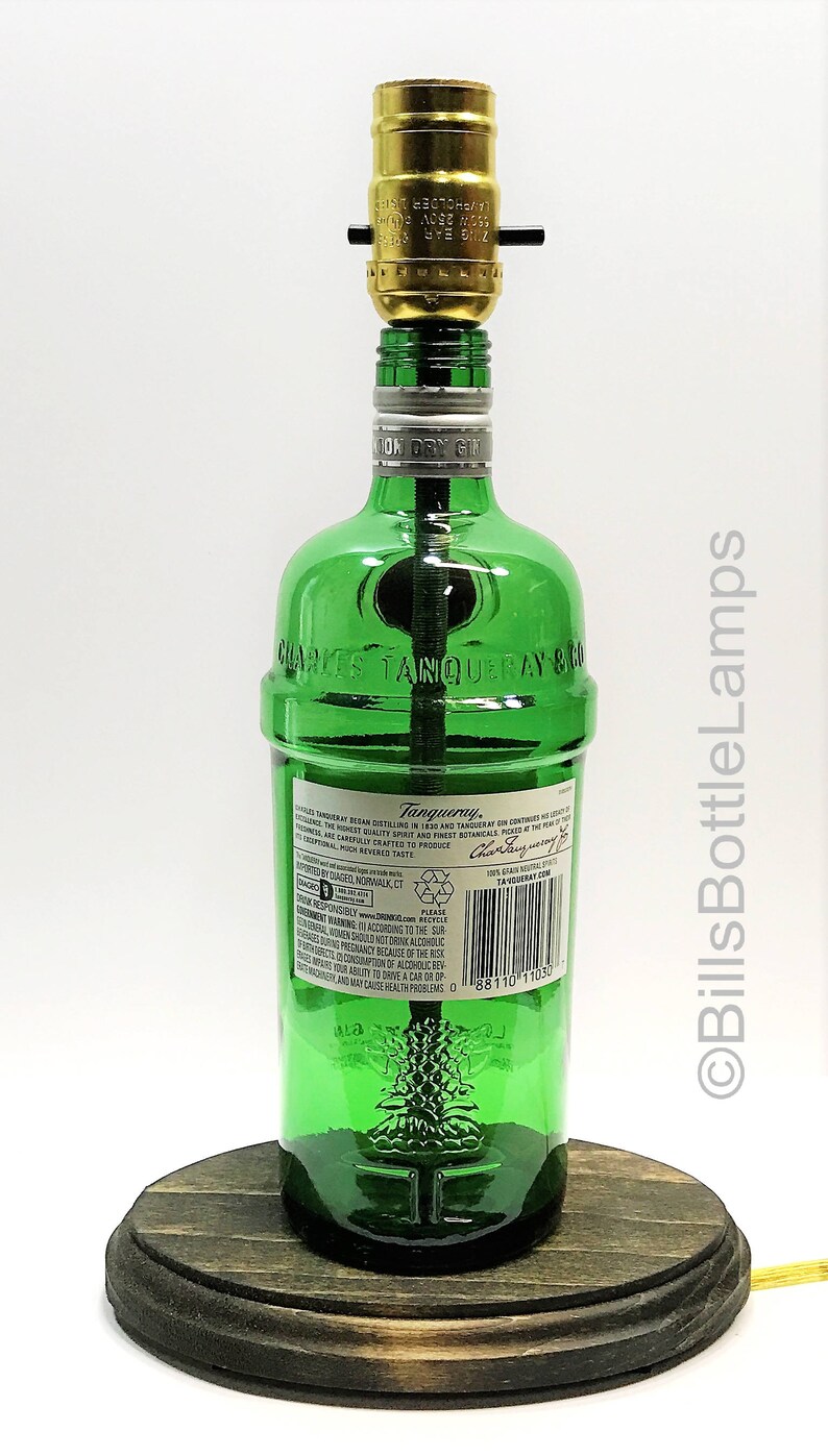 May include: A green glass bottle lamp with a wooden base. The bottle is labeled "Charles Tanqueray & Co. London Dry Gin".
