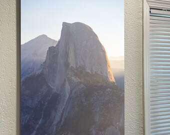 May include: A photograph of Half Dome, a granite cliff in Yosemite National Park, California. The image shows the iconic rock formation with a blue sky and clouds in the background.