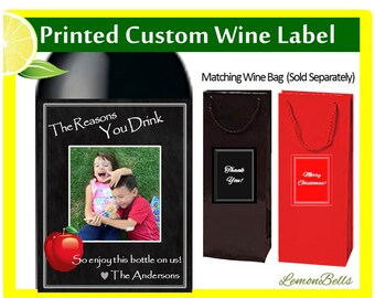 May include: A black and white wine label with a chalkboard background and a photo of two children. The text on the label reads "The Reasons You Drink" and "So enjoy this bottle on us! ❤The Andersons". The label is for a wine bottle and is a custom printed label. The image also shows two wine bags, one black and one red, with the text "Thank You!" and "Merry Christmas!" respectively. The bags are sold separately.