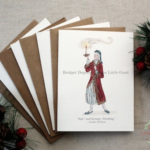 Pu&ograve; includere: Biglietti di Natale ad acquerello con un'illustrazione dickensiana di Scrooge che tiene in mano una candela, con la citazione "Bah, disse Scrooge, Humbug." I biglietti sono abbinati a buste di carta kraft marrone. &Egrave; visibile anche il testo "Bridget Deputy & Some Little Good".