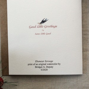 Pu&ograve; includere: Un biglietto di auguri con il testo "Good Little Greetings" e una piccola illustrazione di un uccello. Il biglietto include anche il testo "Ebenezer Scrooge" e il nome dell'artista, Bridget A. Deputy, con un avviso di copyright.