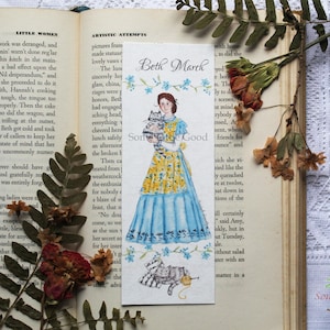 May include: A watercolor bookmark featuring a painting of Beth March from Little Women, holding two kittens. The bookmark is white with blue and yellow floral accents. The text "Beth March" is written in black at the top of the bookmark.