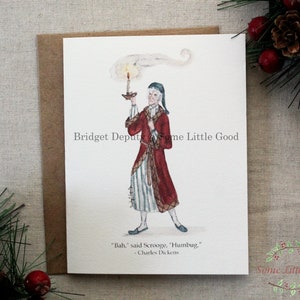 Pu&ograve; includere: Un biglietto di Natale con un'illustrazione ad acquerello di Ebenezer Scrooge che tiene in mano una candela, indossa un cappotto rosso e una cuffia da notte. La citazione "Bah", disse Scrooge, "Humbug", &egrave; sotto l'immagine. Il biglietto &egrave; su una busta marrone.