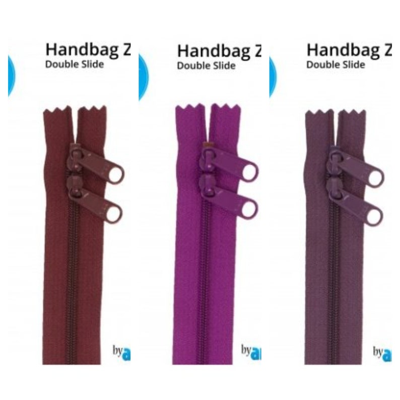 May include: Three zipper pulls with double sliders in burgundy, purple, and mauve. The zippers are labeled "Handbag Z Double Slide" and "by a".