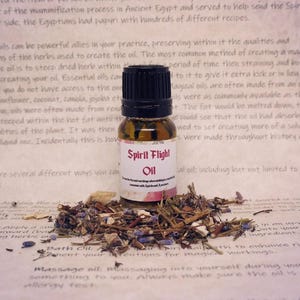 May include: A small glass bottle with a black cap filled with a clear liquid. The bottle has a white label with the text "Spirit Flight Oil" printed on it. The bottle is surrounded by dried herbs and flowers.