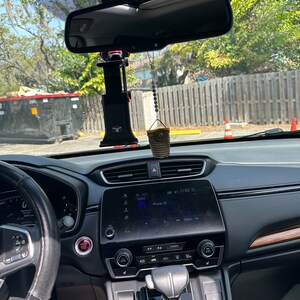 May include: The interior of a black car with a black steering wheel, a black dashboard, and a black gear shift. The car has a digital display screen that says "iPhone (2)" and "Track". There is a red button on the dashboard that says "Start/Stop".