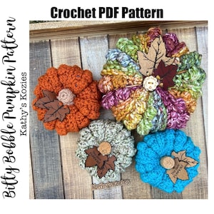 May include: Four crocheted pumpkins in various colors, including orange, teal, green, and brown. Each pumpkin has a small brown leather tag with the text "Hey there pumpkin!" on it.