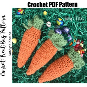 May include: Three crocheted carrot-shaped treat bags with green tops. The bags are filled with colorful candies and are sitting on a bed of green grass.