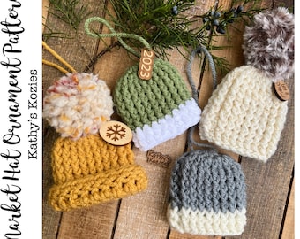May include: Five crocheted hats in different colors, including green, white, yellow, gray, and brown. Each hat has a white brim and a wooden embellishment. The hats are arranged on a wooden surface. The text "Kathy's Kozies" is visible on two of the hats.