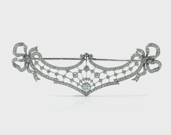 Broche Belle Époque de platino con diamantes calados y extremos en forma de lazo.