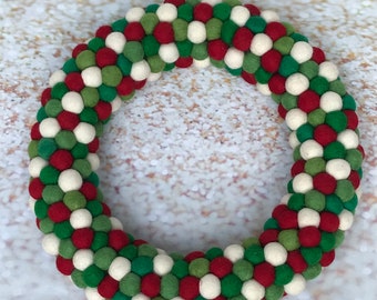 Pode incluir: Uma guirlanda de Natal feita de bolas de feltro em vermelho, verde e branco.