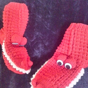 May include: A pair of red knitted slipper socks with white trim and googly eyes. The socks have a textured knit pattern.