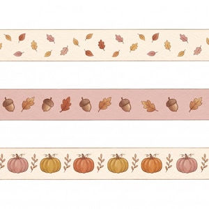 May include: Three strips of decorative adhesive tape. The top strip is cream with small brown, orange, and red leaves. The middle strip is dusty pink with brown acorns and orange leaves. The bottom strip is cream with orange and pink pumpkins.