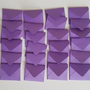 May include: A stack of 20 lavender envelopes, each with a pointed flap. The envelopes are arranged in five rows of four, with the flaps facing the same direction.