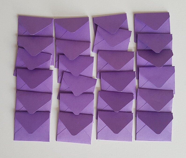 May include: A stack of 20 lavender envelopes, each with a pointed flap. The envelopes are arranged in five rows of four, with the flaps facing the same direction.