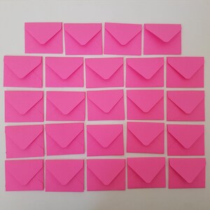 May include: A collection of twenty-one vibrant pink square envelopes, arranged on a white surface. The envelopes are evenly spaced and form a grid, highlighting their consistent shape and colour. Suitable for stationery or craft purposes.