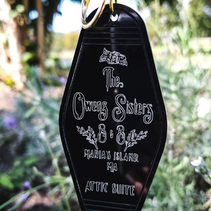 May include: Black motel key tag with white text that reads "The Owens Sisters B & B Maria's Island MA Attic Suite".