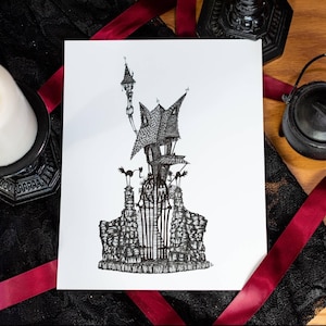 May include: A monochrome pen and ink drawing of a haunted house with a tall tower and a wrought iron gate. The artwork is on white paper, with a black lace and red ribbon background.