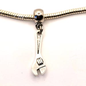 May include: Silver charm in the shape of a wrench, hanging from a silver chain.