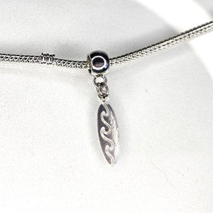 Op de afbeelding: Een zilveren ketting met een zilveren bedel met een golfontwerp.