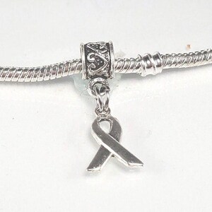 May include: Silver charm bracelet with a silver ribbon charm. The ribbon charm is a symbol of support and awareness.